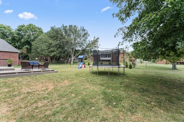 view of yard featuring a trampoline, a deck, and a playground