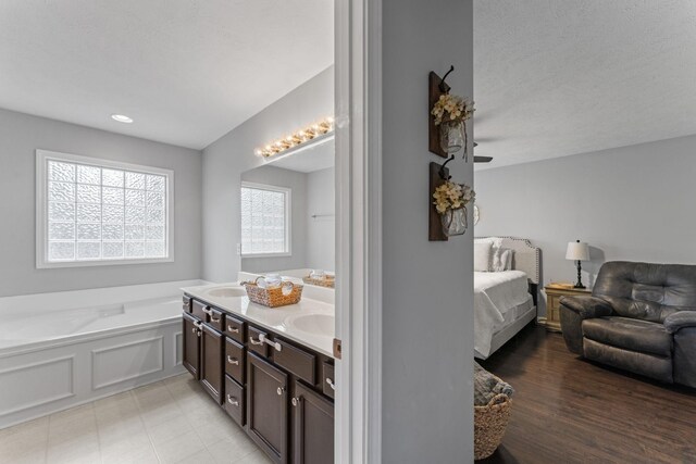 bathroom featuring a textured ceiling, a bath, wood-type flooring, and vanity