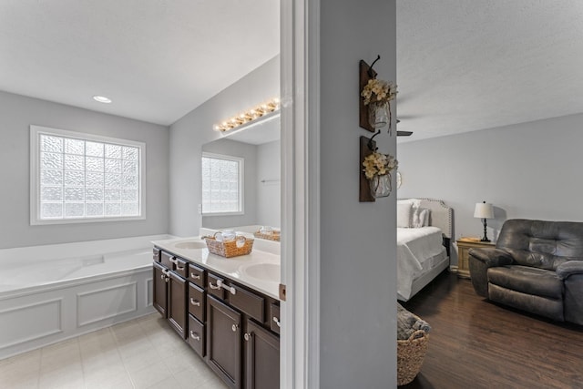 bathroom featuring a sink, a bath, and double vanity