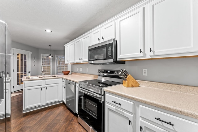 kitchen featuring stainless steel appliances, a sink, white cabinetry, hanging light fixtures, and light countertops