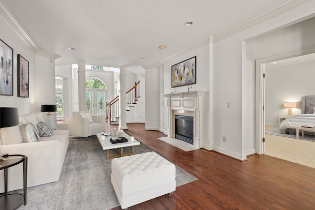 living room featuring decorative columns, wood-type flooring, and ornamental molding