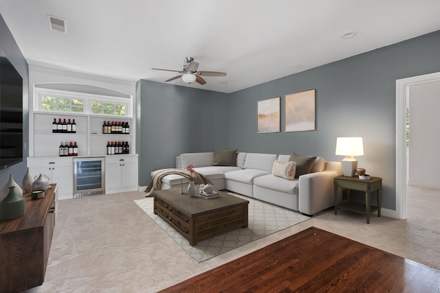 carpeted living room with ceiling fan and wine cooler