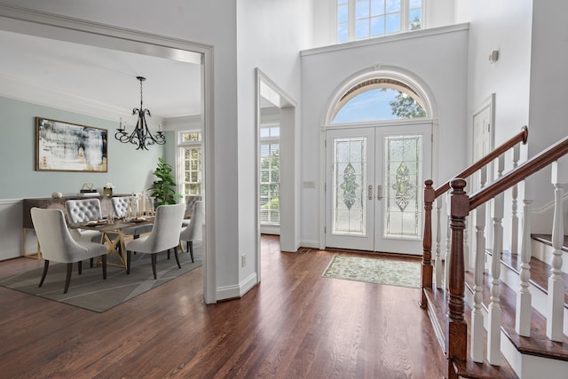 foyer featuring dark hardwood / wood-style floors, a towering ceiling, an inviting chandelier, and french doors