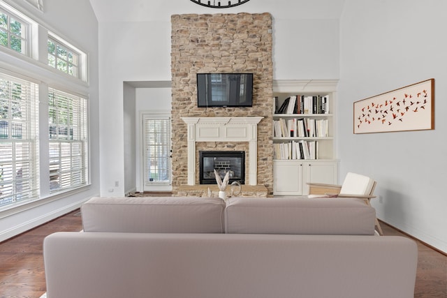 living room featuring a fireplace, a high ceiling, built in shelves, and dark hardwood / wood-style floors