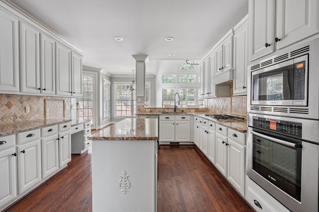 kitchen featuring a center island, stainless steel appliances, dark wood-type flooring, and light stone countertops