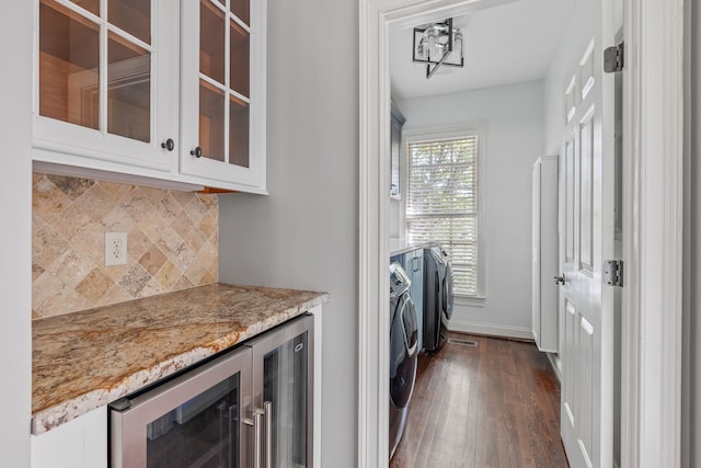 clothes washing area with dark wood-type flooring, wine cooler, and washing machine and clothes dryer