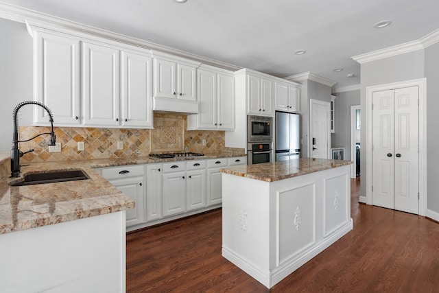 kitchen with appliances with stainless steel finishes, dark hardwood / wood-style floors, tasteful backsplash, sink, and a center island