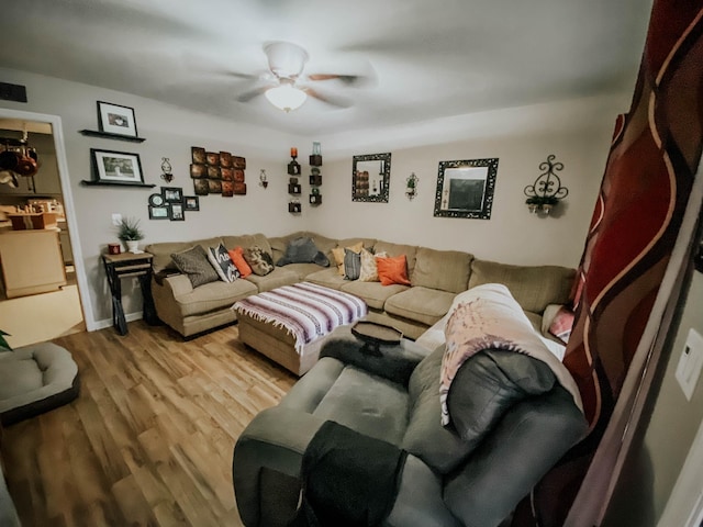 living area featuring baseboards, ceiling fan, and wood finished floors