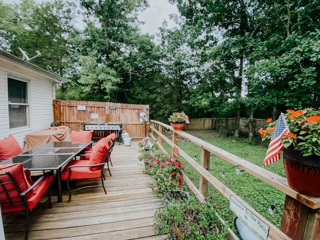 wooden deck with grilling area, outdoor dining area, and a fenced backyard