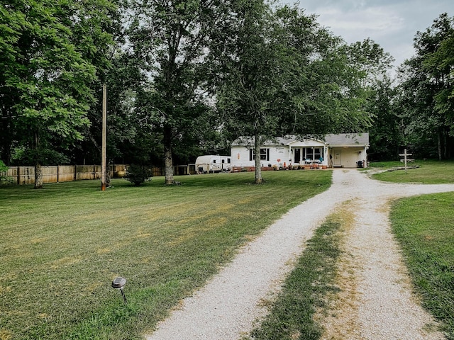 view of front of property featuring driveway, a front lawn, and fence