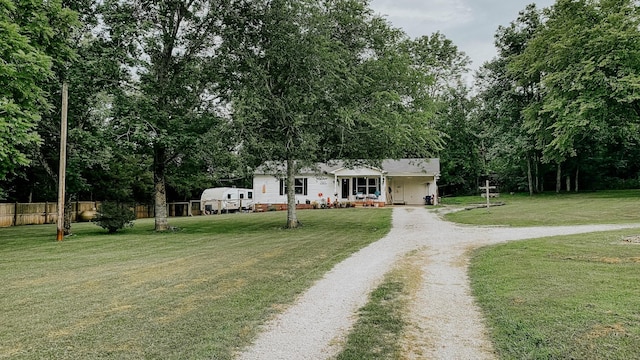 view of front facade featuring a front lawn, covered porch, driveway, and fence