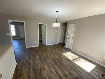 unfurnished dining area with dark wood-type flooring and a notable chandelier