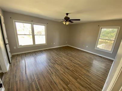 empty room with a ceiling fan, baseboards, and dark wood-style flooring