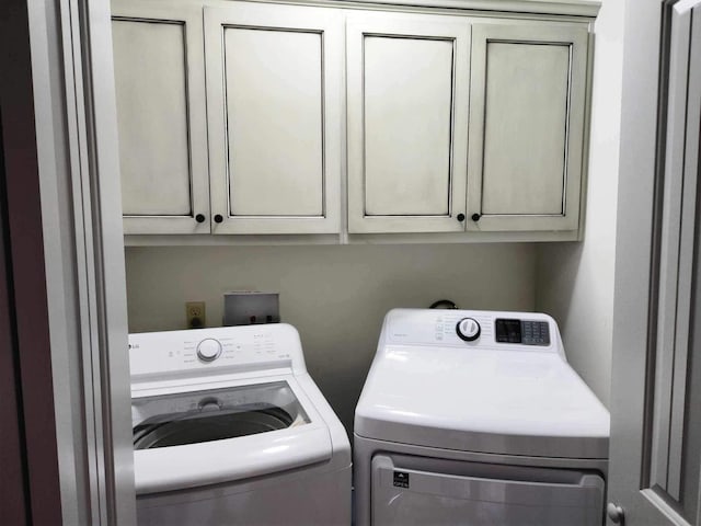 washroom featuring separate washer and dryer and cabinet space