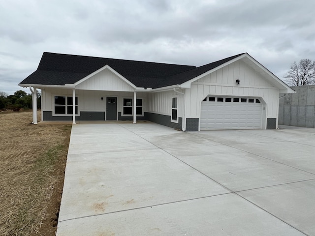 view of front of house featuring a garage, brick siding, board and batten siding, and driveway