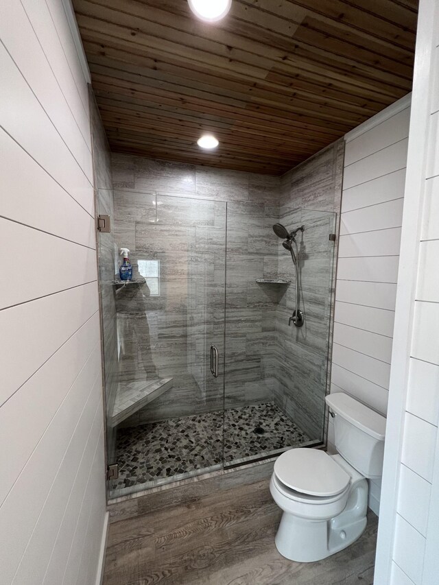 bathroom featuring wooden ceiling, toilet, a stall shower, and wood finished floors