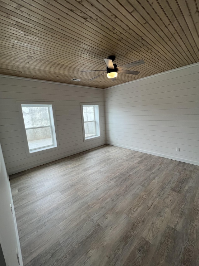 spare room with wood ceiling, wood finished floors, visible vents, and ceiling fan