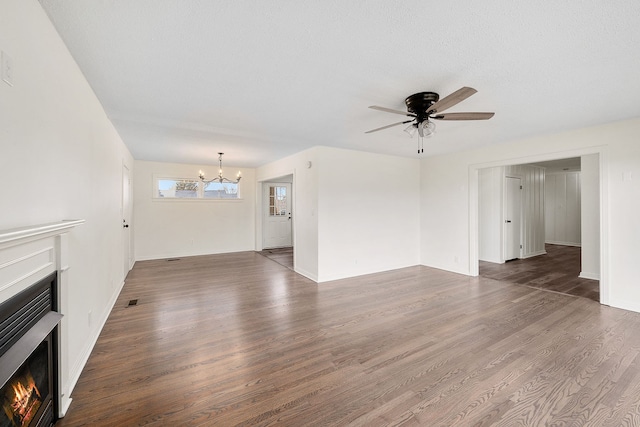 unfurnished living room with ceiling fan with notable chandelier and dark wood-type flooring