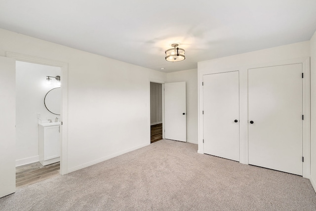 unfurnished bedroom featuring light colored carpet and ensuite bathroom