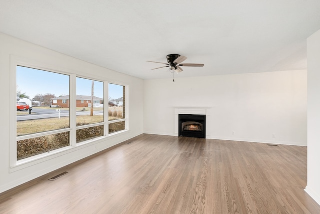 unfurnished living room with light wood-type flooring, plenty of natural light, and ceiling fan