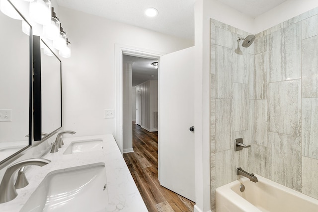 bathroom with hardwood / wood-style floors, tiled shower / bath combo, a textured ceiling, and vanity