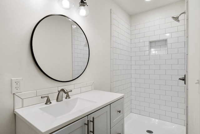 bathroom featuring tiled shower and vanity