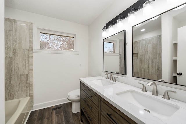 full bathroom featuring a wealth of natural light, toilet, hardwood / wood-style flooring, and vanity