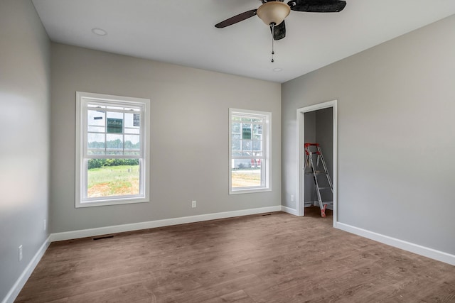 empty room featuring ceiling fan, a wealth of natural light, and hardwood / wood-style floors