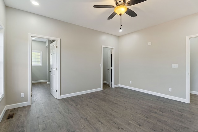 unfurnished bedroom featuring dark wood-type flooring, ceiling fan, and a spacious closet