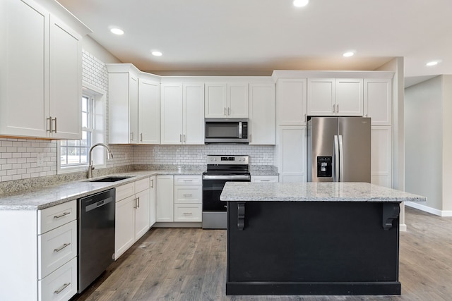 kitchen with light hardwood / wood-style flooring, stainless steel appliances, sink, and a center island