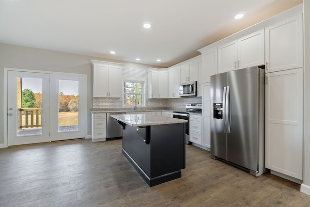 kitchen with dark hardwood / wood-style floors, a breakfast bar area, stainless steel appliances, a center island, and white cabinetry