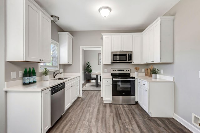 kitchen featuring a sink, stainless steel appliances, dark wood-type flooring, white cabinets, and light countertops