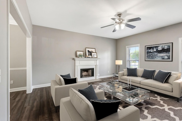 living room featuring dark wood-style floors, a fireplace with flush hearth, baseboards, and ceiling fan