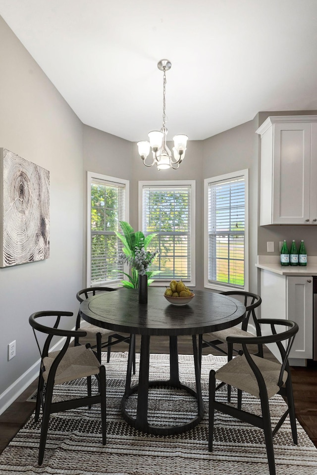 dining space with dark wood finished floors, a notable chandelier, a healthy amount of sunlight, and baseboards