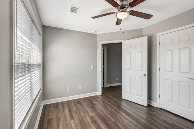 unfurnished bedroom featuring dark wood finished floors, visible vents, a ceiling fan, and baseboards