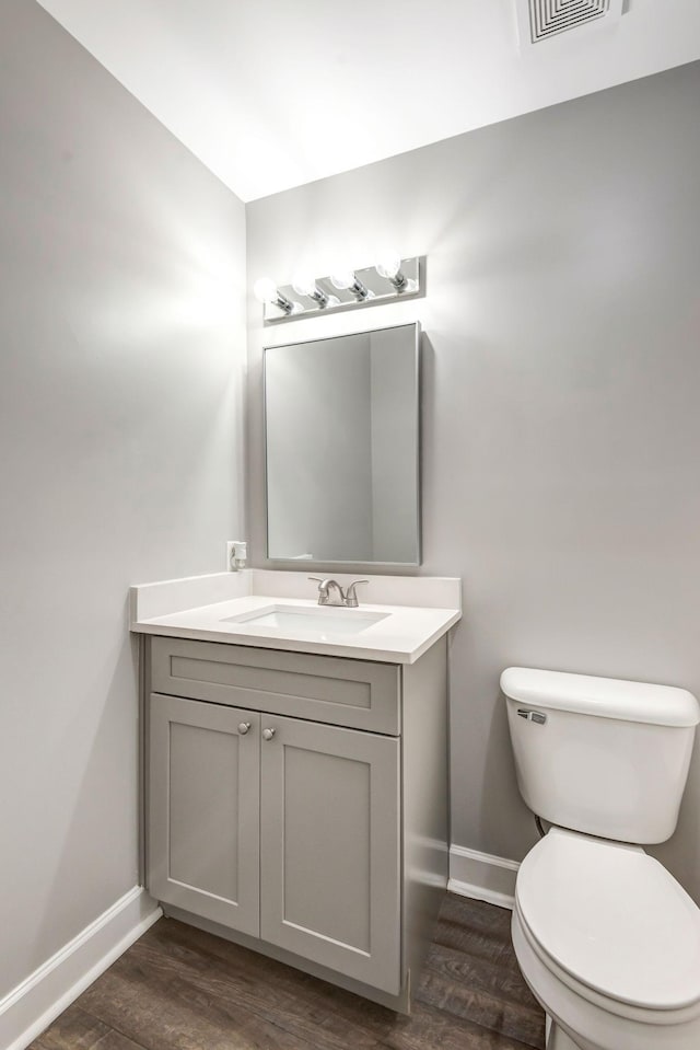 bathroom with visible vents, toilet, wood finished floors, baseboards, and vanity