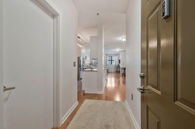 hall with light wood-type flooring and baseboards