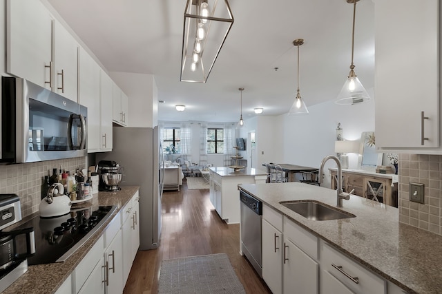 kitchen with backsplash, dark hardwood / wood-style floors, white cabinetry, appliances with stainless steel finishes, and sink