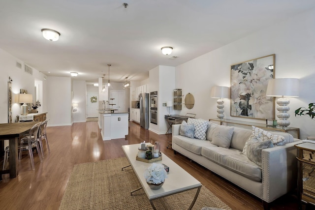 living area featuring wood finished floors, visible vents, and baseboards