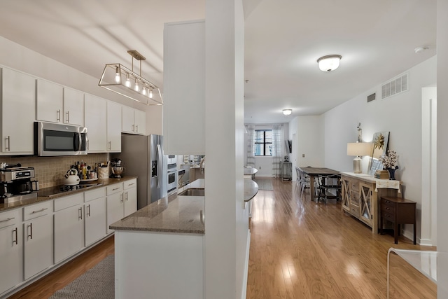 kitchen featuring light hardwood / wood-style floors, stainless steel appliances, hanging light fixtures, and white cabinetry