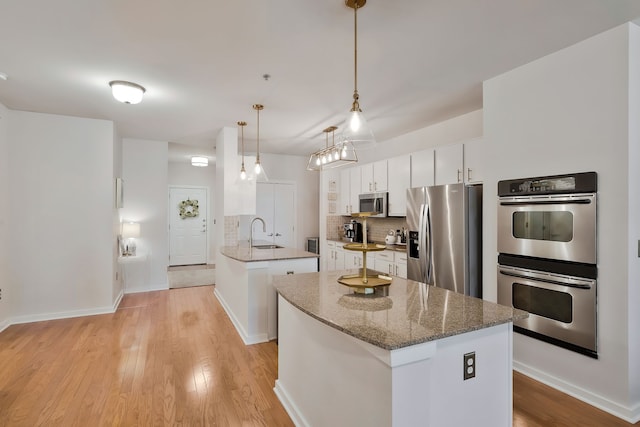 kitchen featuring stainless steel appliances, light hardwood / wood-style flooring, decorative backsplash, and white cabinets