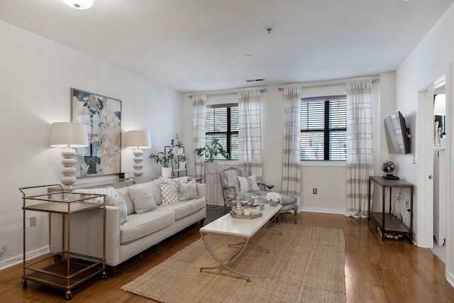 living room featuring a wealth of natural light and dark wood-type flooring