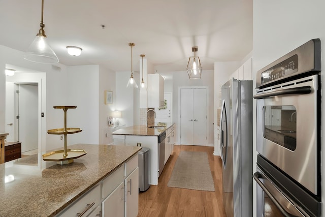 kitchen featuring appliances with stainless steel finishes, light hardwood / wood-style floors, white cabinetry, sink, and a center island