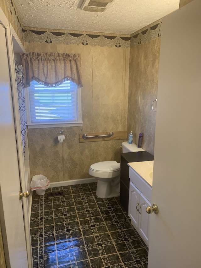 bathroom featuring tile patterned flooring, toilet, a textured ceiling, and vanity