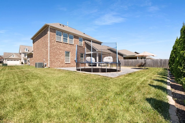 rear view of house featuring cooling unit, a patio, and a yard