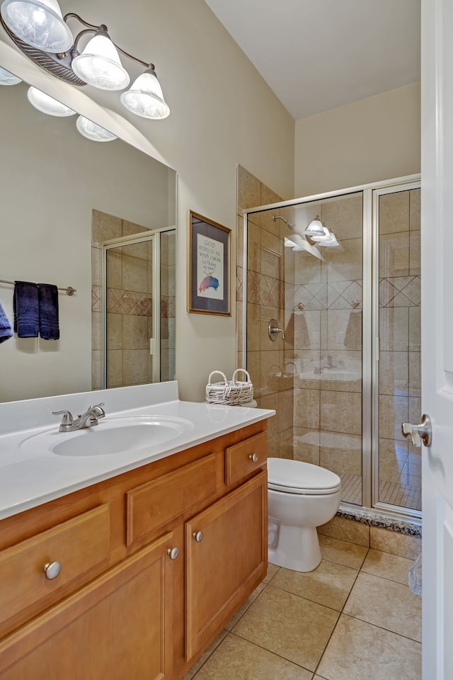 bathroom featuring tile patterned floors, toilet, vanity, and a shower with shower door