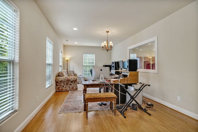 home office with light wood-type flooring and a chandelier