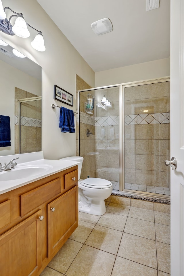 bathroom featuring tile patterned flooring, toilet, walk in shower, and vanity