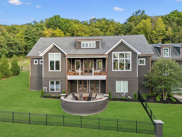 rear view of property with a patio, an outdoor fire pit, a balcony, brick siding, and a lawn