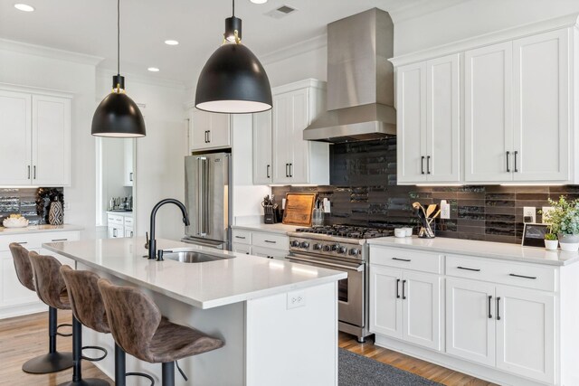 kitchen with sink, wall chimney exhaust hood, decorative backsplash, light hardwood / wood-style floors, and high end appliances